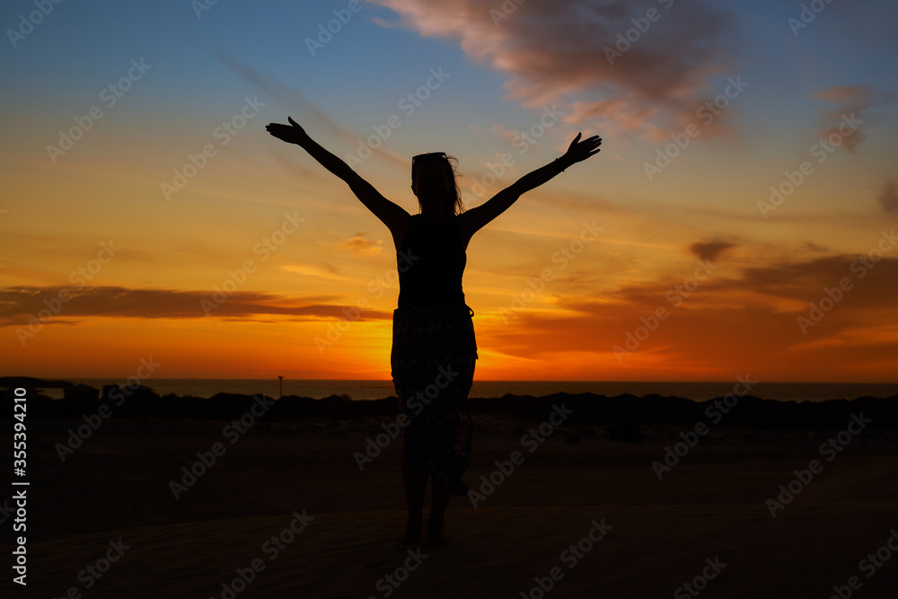 A woman standing against the backdrop of the setting sun