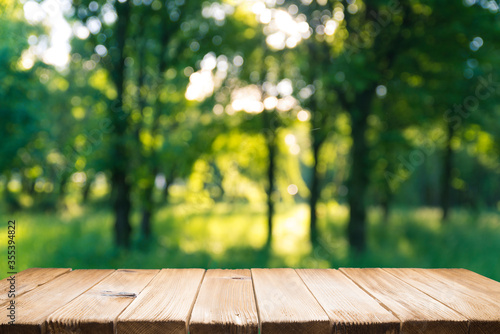 Empty wooden deck table with park bokeh background.