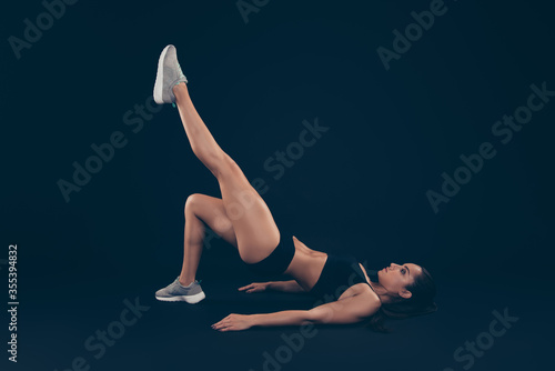 Full length profile photo short sport suit lady doing body weight exercise raise leg up isolated black dark background photo