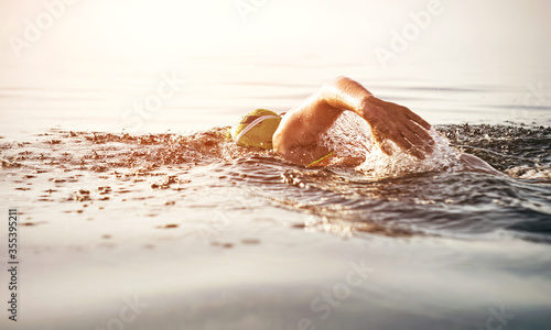 Unknown triathlon swimmer at sea. athletic young woman swimming freestyle in morning open water