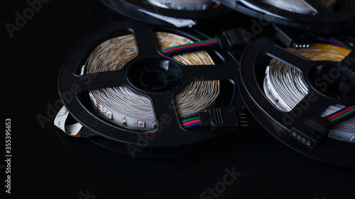 Coils of rgb led strip on a black table. Led strip for creative lighting collected in a black coil, tools for lighting and light effects.