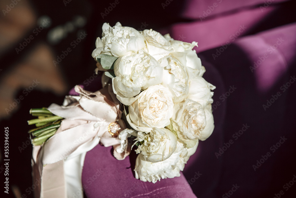 A bouquet of flowers lies on a purple cloth. Wedding rings in a glass box. Wedding concept. Wedding trend A bouquet of flowers lies on a purple cloth. Wedding rings in a glass box. Wedding concept. Wedding trend