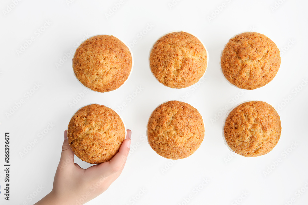 Children's hand takes one of the cupcakes located on a white background, shot from above Children's hand takes one of the cupcakes located on a white background, shot from above
