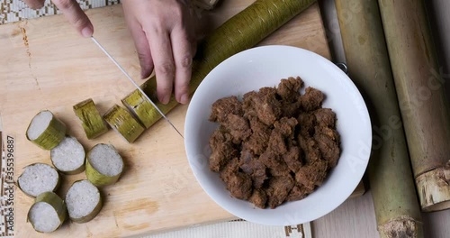 Hand cutting the lemang, a glutinous rice normally served with rendang, a popular traditional food in Malaysia, Indonesia and Singapore during Hari Raya festive photo