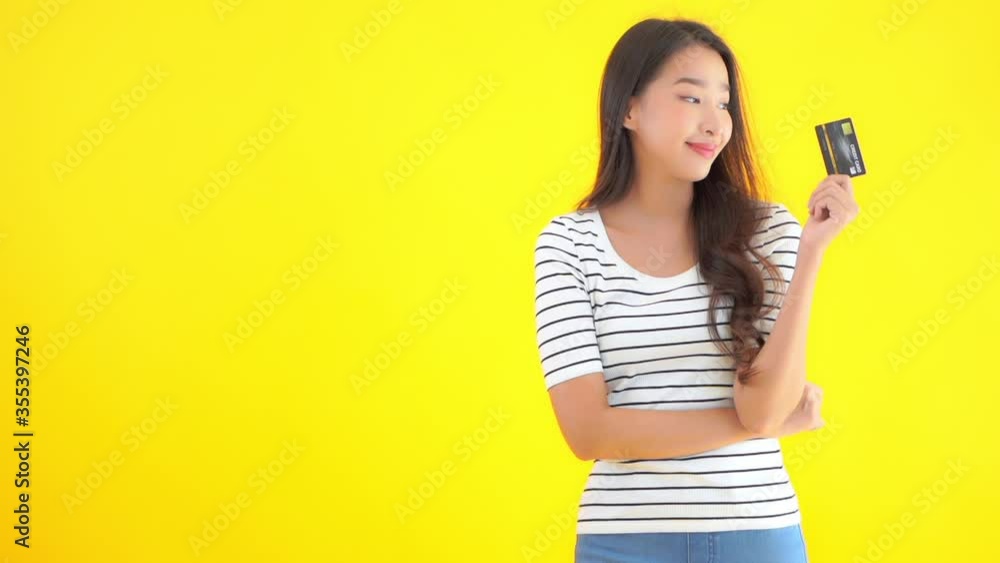 A young attractive Asian woman holds up a black credit card. A young attractive Asian woman holds up a black credit card.
