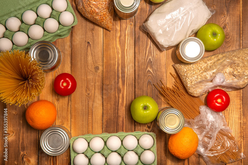 Food delivery during coronavirus quarantine: canned food, cereals. Long-term storage of food and basic necessities close-up on a wooden background. Flat lay