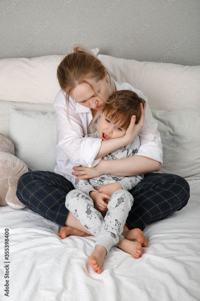 Mother hugs and measures the temperature of the child. The theme of the coronavirus. To remove a fever and chills Mother hugs and measures the temperature of the child. The theme of the coronavirus. To remove a fever and chills
