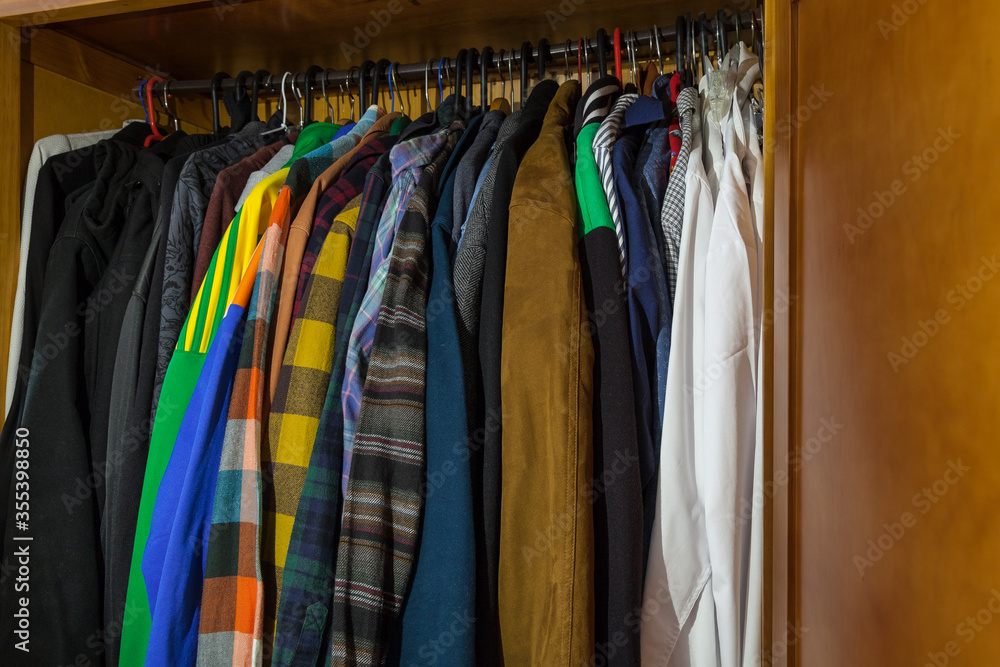 Wardrobe full of clothes of different styles on hangers. Concept of changing the wardrobe by season, second-hand sales and sales in the textile sector with negative space.