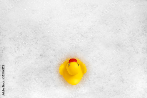 High Angle View of yellow rubber duck in bath swimming in foam water. Yellow rubber ducklings in soapy foam.