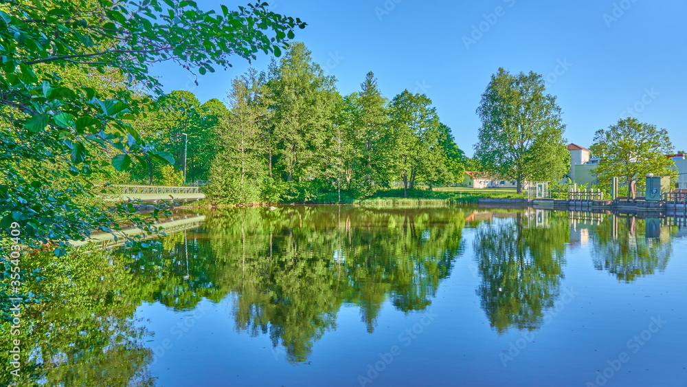 Fototapeta premium The green trees reflected in the water, Spring, Sweden