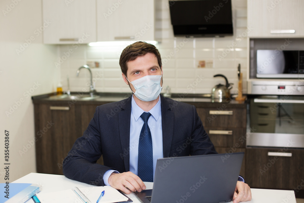 man in a mask works at a computer at home. Business communication concept. man in a mask works at a computer at home. Business communication concept.