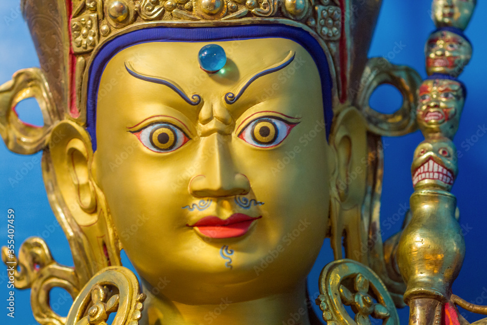 Close up of gold covered face of tibetan buddhist master Guru Rimpoche or Padmasambhava.