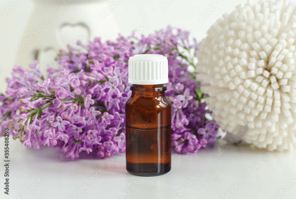 Small bottle with essential oil (tincture, infusion, perfume) and lilac flowers. Aromatherapy, spa and herbal medicine ingredients. Small bottle with essential oil (tincture, infusion, perfume) and lilac flowers. Aromatherapy, spa and herbal medicine ingredients.