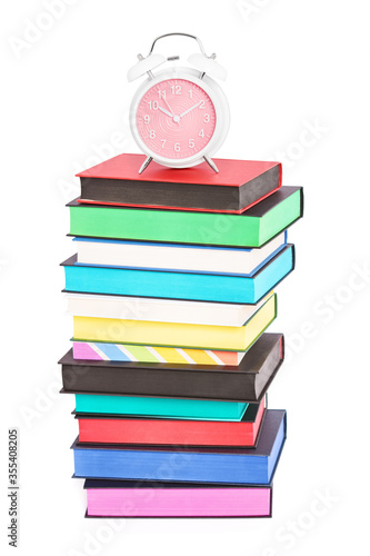 An alarm clock on top of stack of colorful books