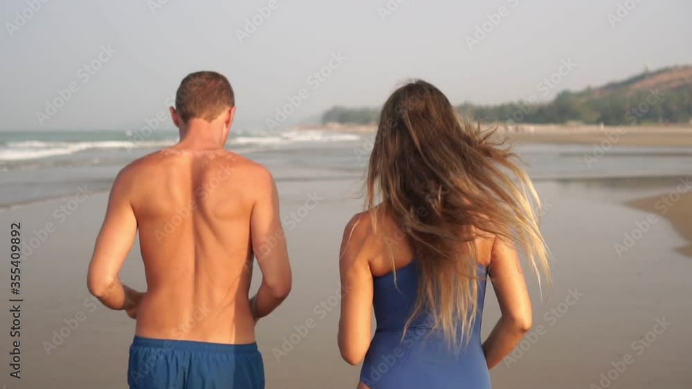 A young couple, a man and a woman, are running along the sea beach, slow motion A young couple, a man and a woman, are running along the sea beach, slow motion