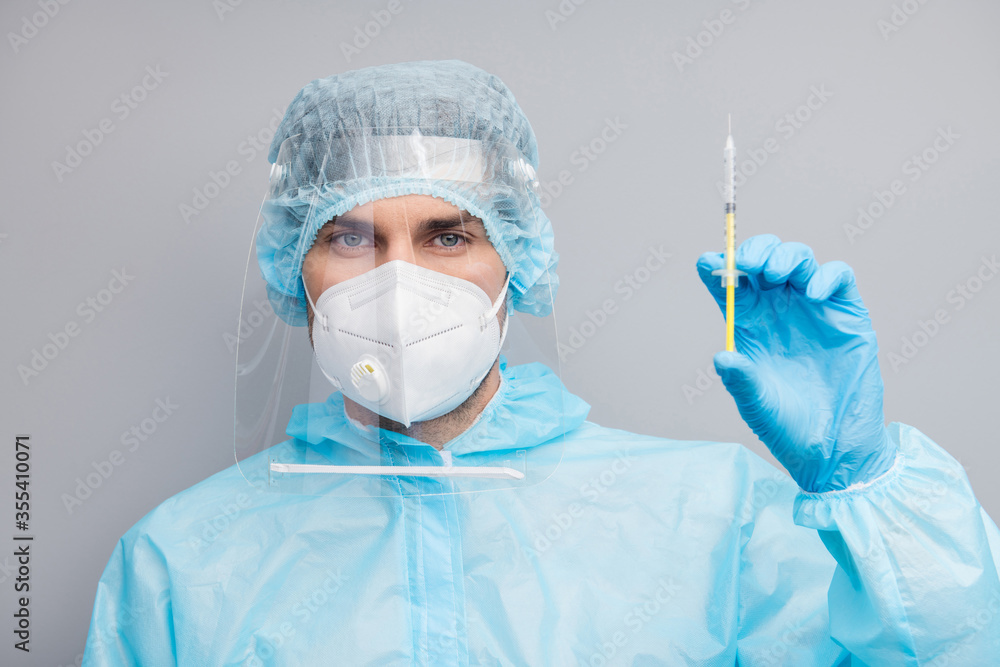Closeup photo of professional guy expert doc virology clinic prepare antidote injection wear respirator hazmat blue uniform plastic facial protective shield isolated grey color background Closeup photo of professional guy expert doc virology clinic prepare antidote injection wear respirator hazmat blue uniform plastic facial protective shield isolated grey color background