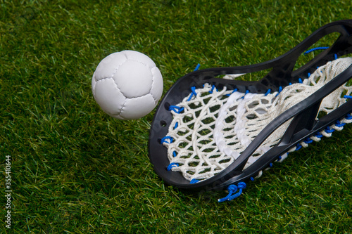 Lacrosse stick and white ball on grass background. Team sport concept.