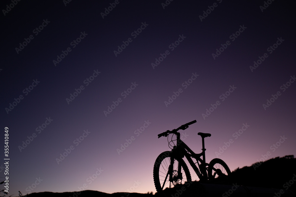 Fototapeta premium Silhouette of Mountain Bike, Dirt bike on the car roof rack in the countryside at the sunset,Bicycles built for traveling on dirt road.