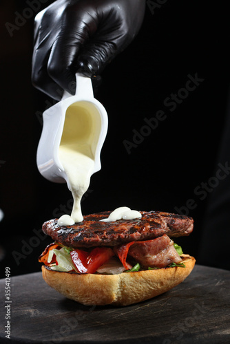 The chef adds white sauce to the Burger. Cooking a sandwich. An unrecognizable photo. A copy of this place. photo