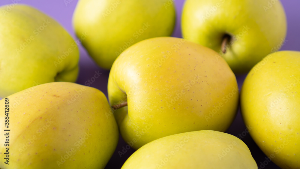 Yellow apples on purple background. Set of green apples. Scattered ripe juicy apples. Healthy snack. Bright colors. Yellow apples on purple background. Set of green apples. Scattered ripe juicy apples. Healthy snack. Bright colors.