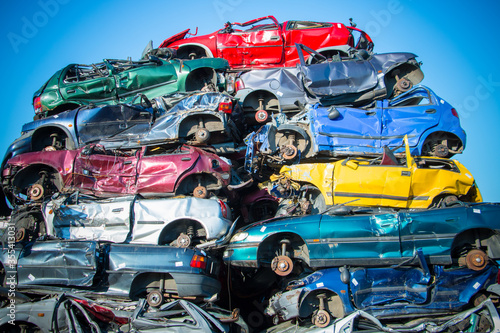 Obraz na płótnie Stacked old cars on a yunk yard in different colours with a blue skye