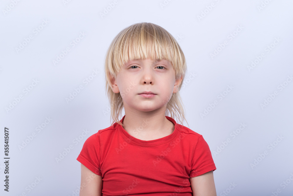 Portrait of serious fair-haired boy in red t-shirt on white background. Portrait of serious fair-haired boy in red t-shirt on white background.