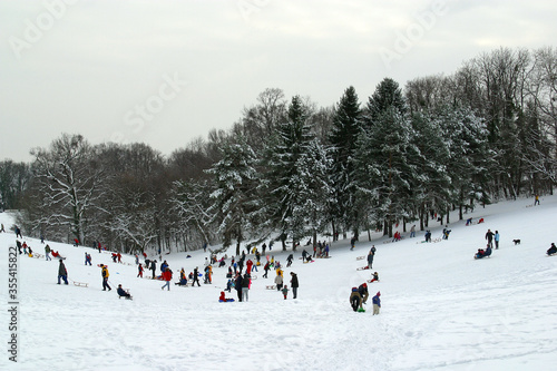 Landscape view of a snowy hill with families with children sledging and having fun in snow, Cmrok in Zagreb, Croatia