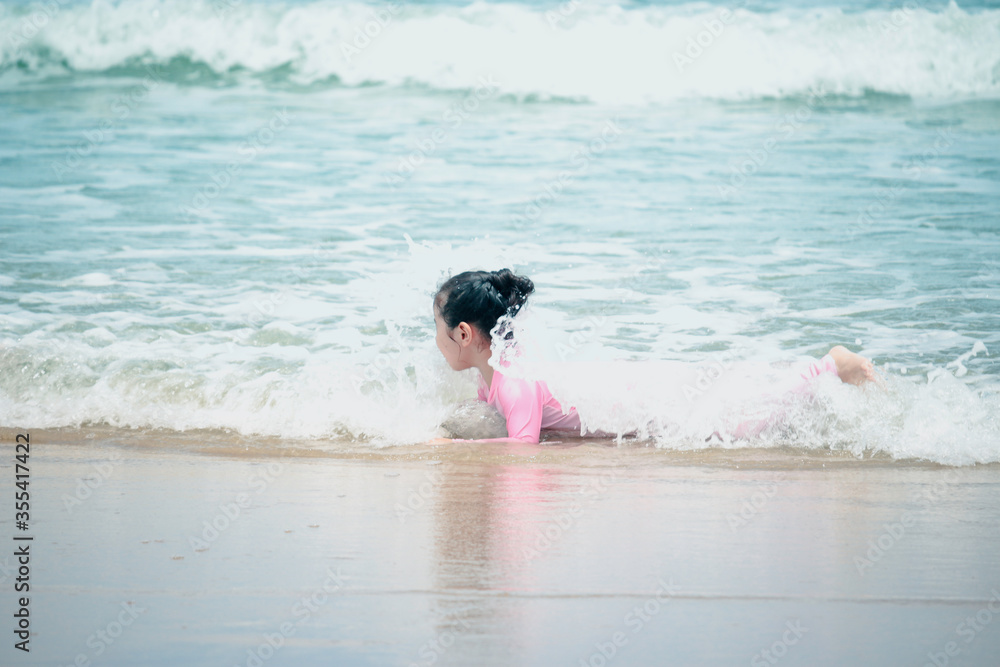 Cute kid having fun on sandy summer with blue sea, happy little girl playing on tropical beach, child with ocean waves Cute kid having fun on sandy summer with blue sea, happy little girl playing on tropical beach, child with ocean waves