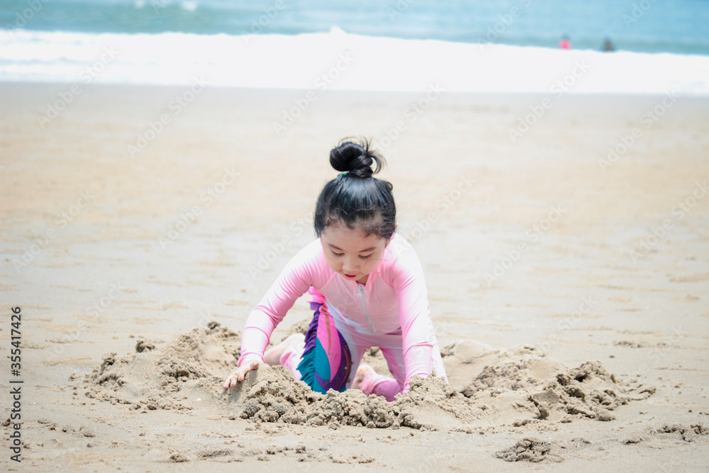 Cute kid having fun on sandy summer with blue sea, happy little girl making sand castle, playing with sandat on tropical beach Cute kid having fun on sandy summer with blue sea, happy little girl making sand castle, playing with sandat on tropical beach