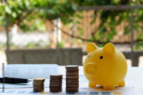 Coin and yellow piggy bank on the white table, Saving money concepts. Garden background