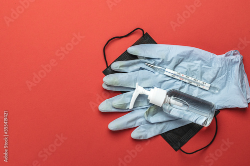Surgical protective Mask isolated. Pandemic infection covid protection with Medical surgical mask, sanitizer gel, thermometer and lab gloves on red. Dangerous Novel virus COVID-19, pandemic risk alert