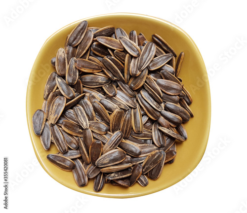 Unpeeled sunflower seeds in bowl isolated on white background. Top view