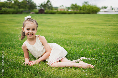 happy little girl on the beach. little girl in a white dress. little girl lying on the grass. little girl walking on the road