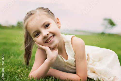 Beautiful girl walks in the park. Summer walks and relaxation. Smiling child.