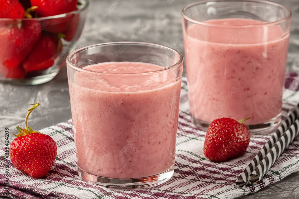 Strawberry smoothie with milk in a glass on a gray background, healthy eating for breakfast and snacks Strawberry smoothie with milk in a glass on a gray background, healthy eating for breakfast and snacks