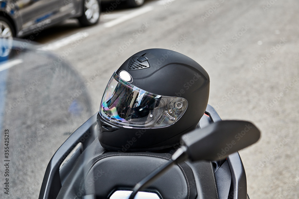 Fototapeta premium Moto scooter 125cc aparcada en la calle con casco 