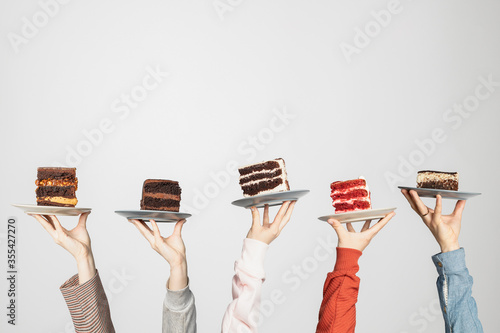 Concept for cafe or bakery with desserts: plates with different cakes in people's hands, place for your text