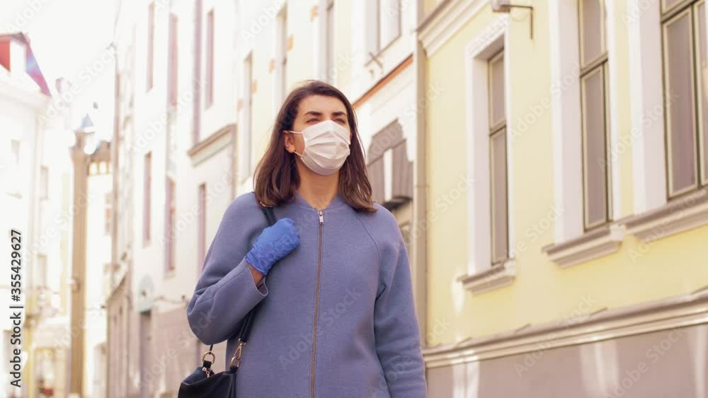 health, safety and pandemic concept - young woman wearing black face protective medical mask and gloves walking in city health, safety and pandemic concept - young woman wearing black face protective medical mask and gloves walking in city