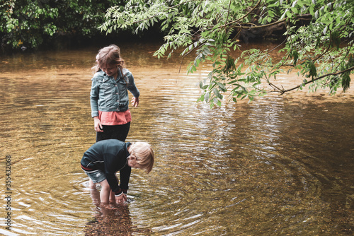 Children playing outside in a shallow stream paddling in the water photo