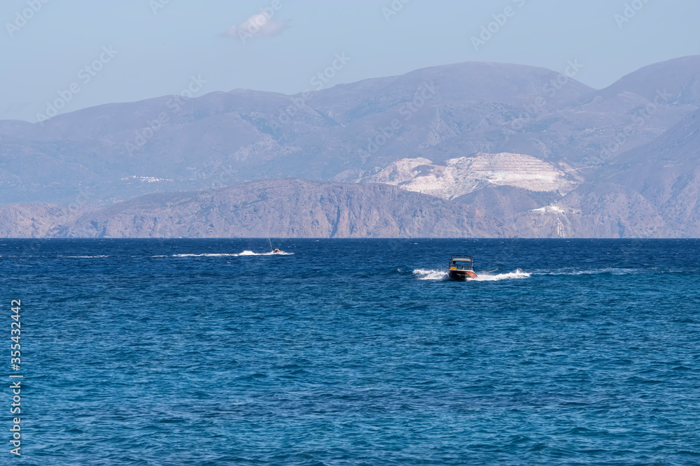 Summer sea view from coast with white yaht and mountains in background, Greece