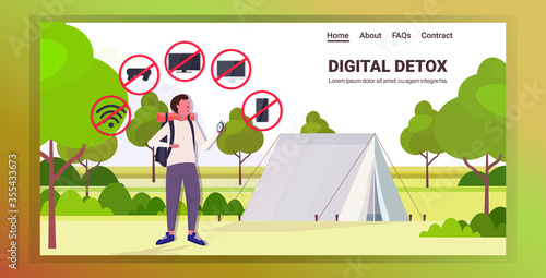 traveler with backpack holding compass gadgets in red prohibition signs digital detox concept guy hiker abandoning devices campsite background horizontal full length copy space vector illustration