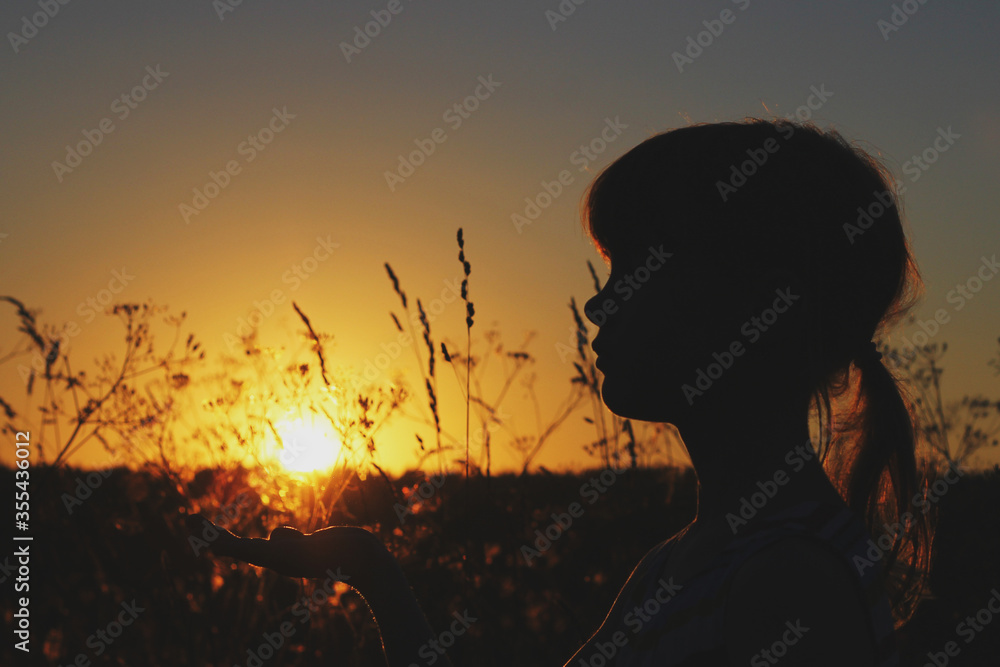 silhouette portrait of a girl at sunset in field. The sun in the palm of your hand silhouette portrait of a girl at sunset in field. The sun in the palm of your hand