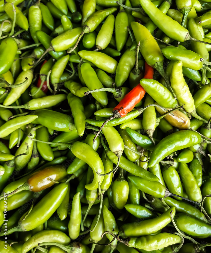 The green raw peppers are in a basket. The green raw peppers are in a basket.