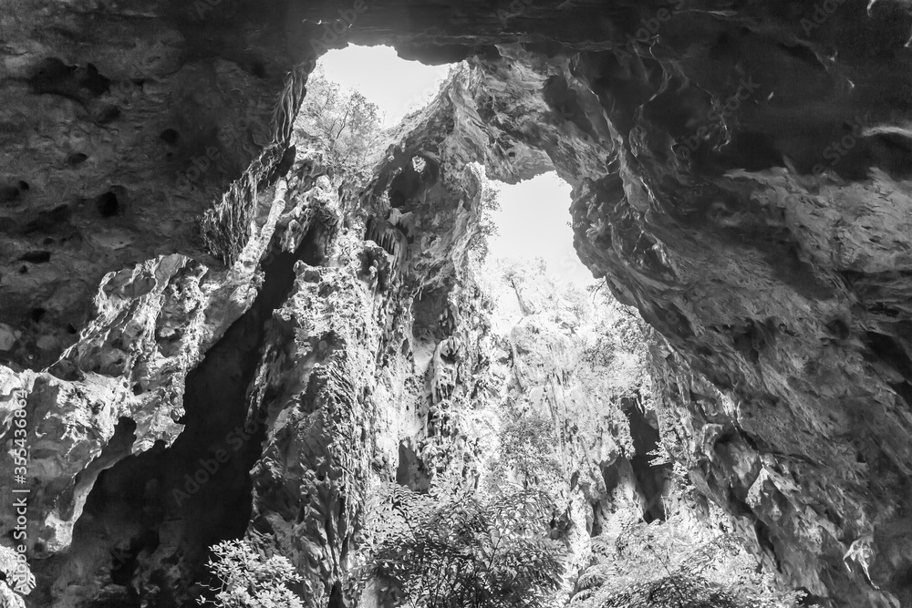 A light chimney passing through a cave with stalactites and stalagmites at Tham Phraya Nakhon Cave, Sam Roi Yot District Prachuap Khiri Khan Province, Thailand. Black and White Nature Background A light chimney passing through a cave with stalactites and stalagmites at Tham Phraya Nakhon Cave, Sam Roi Yot District Prachuap Khiri Khan Province, Thailand. Black and White Nature Background