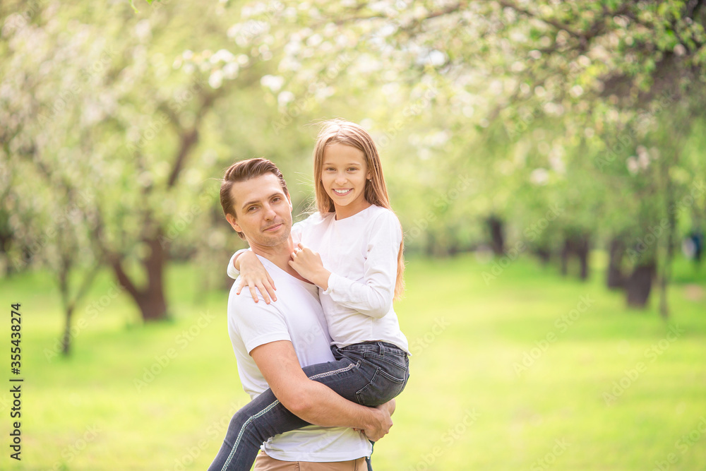 Family of father and daughter in blooming cherry garden Family of father and daughter in blooming cherry garden