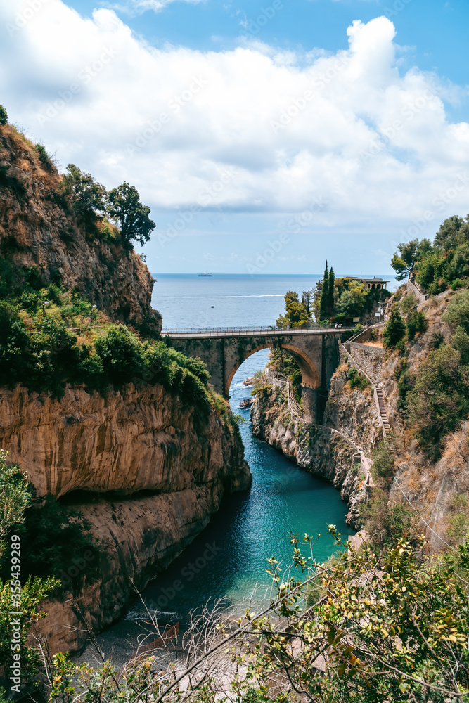 Architectural landmark, stone bridge. A view of the Fiordo of Furore in Amalfi coast, Travel and vacation concept. Summer day. public beach closed. Vertical photo. Italy.