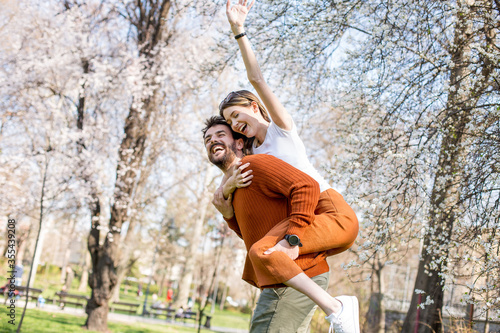 Man and woman doing a piggyback outside, enjoying their time.