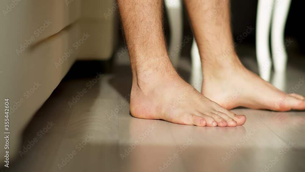 Early in the morning, a man gets out of bed with bare feet on a light floor Early in the morning, a man gets out of bed with bare feet on a light floor