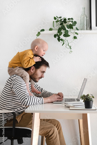 Father working with his baby boy in home office with laptop. Work from home concept © Catherine Chin