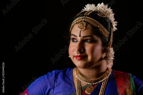 Beautiful bharatnatyam dancer standing in front of a dark background. 
 photo